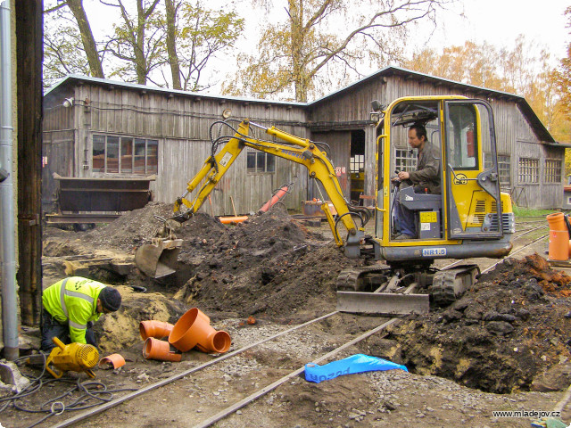 Fotografie Bagr zasypává, zatímco Honza dopojuje okap ze střechy na nový řad. 